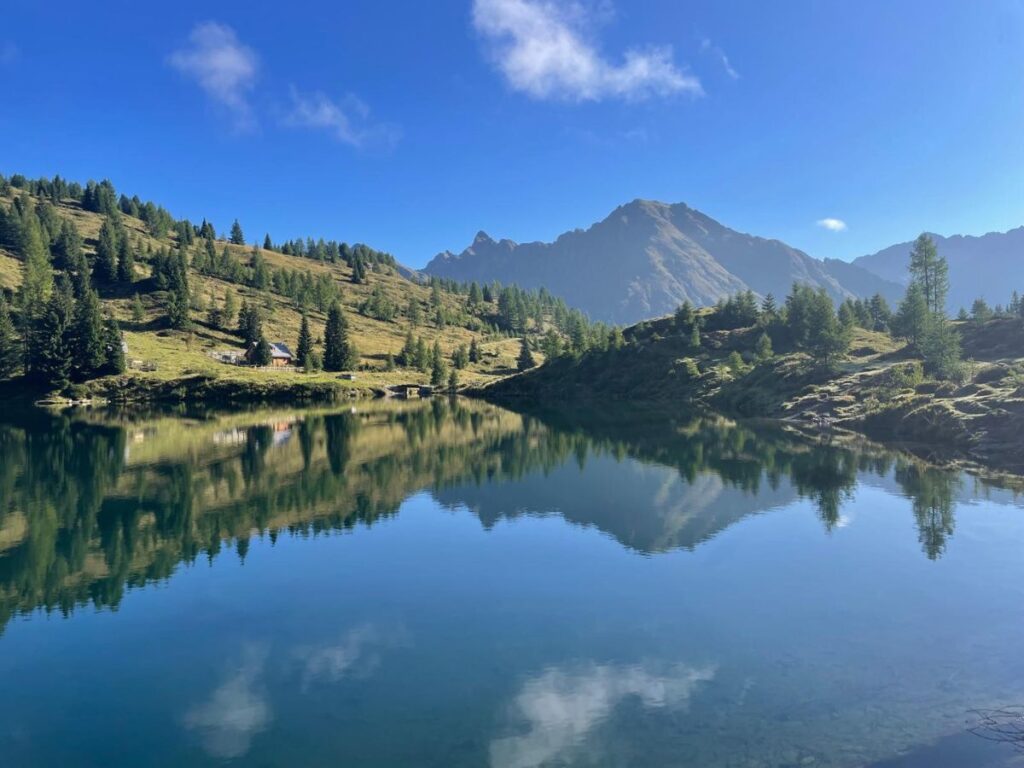 Blick auf den Wirpitschsee in Weißpriach, in dem sich der blaue Himmel spiegelt.