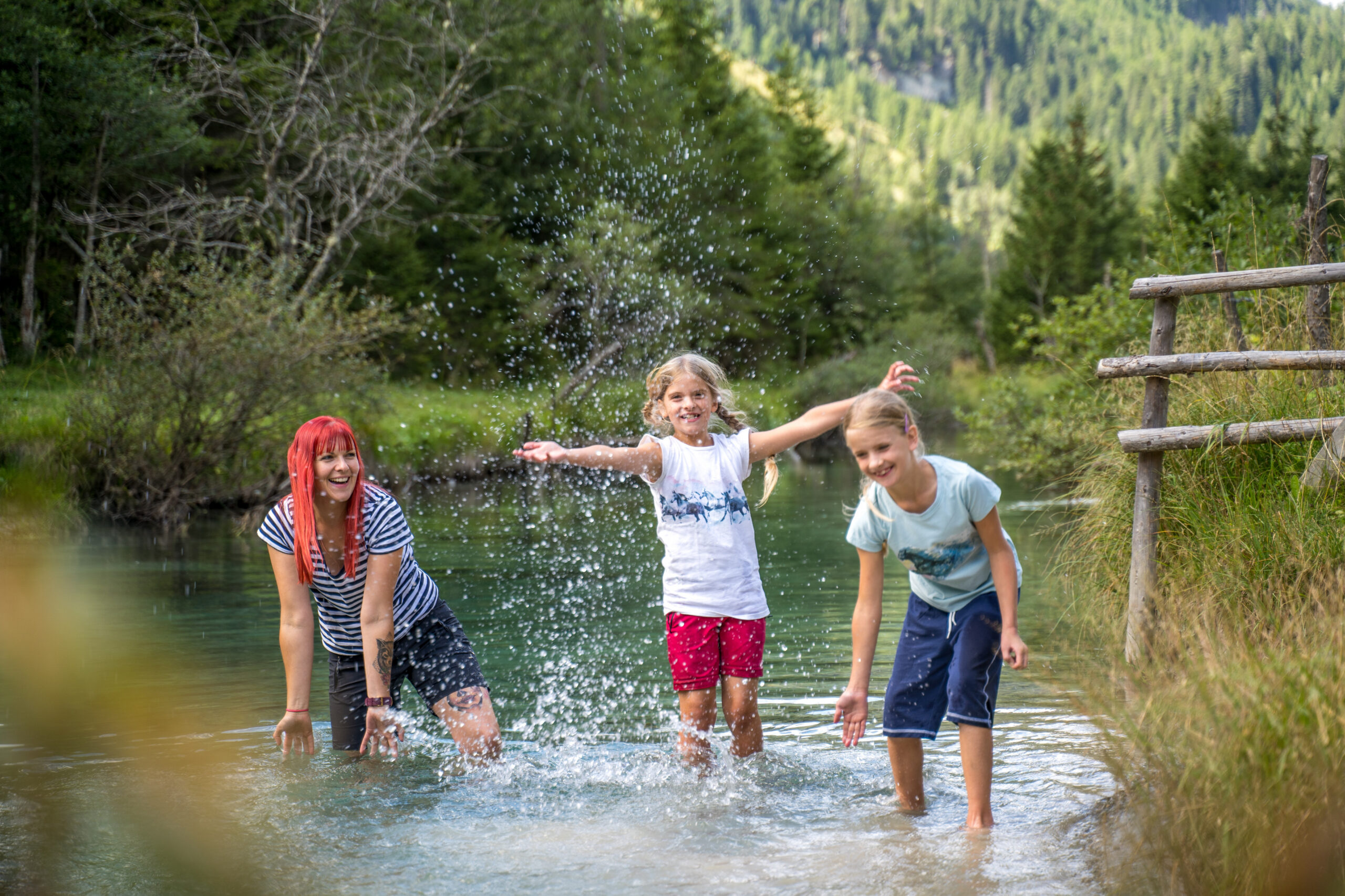 Eine Frau und zwei Kinder spielen im Wasser der Longa